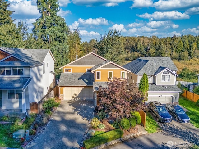 traditional-style house with fence, an attached garage, concrete driveway, and a wooded view