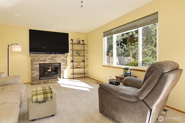 carpeted living room with a brick fireplace, baseboards, and visible vents