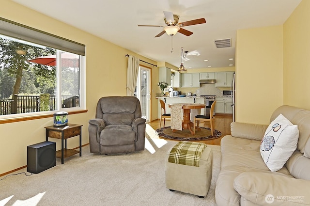 living room featuring light carpet, a ceiling fan, baseboards, recessed lighting, and visible vents