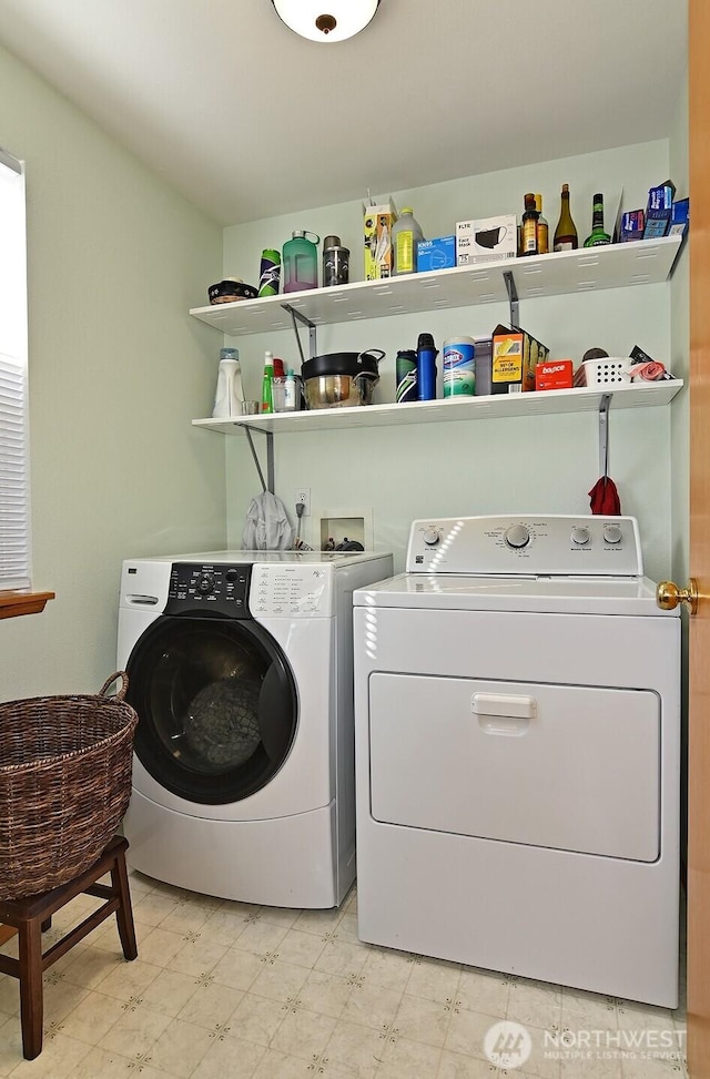 clothes washing area with light floors, laundry area, and washer and dryer