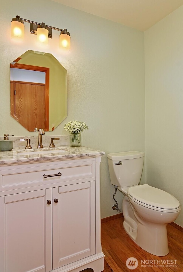 bathroom with baseboards, vanity, toilet, and wood finished floors