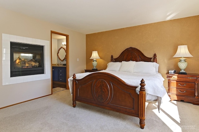 bedroom featuring a sink, a fireplace, connected bathroom, and light colored carpet