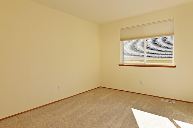 unfurnished room featuring baseboards, visible vents, and light carpet