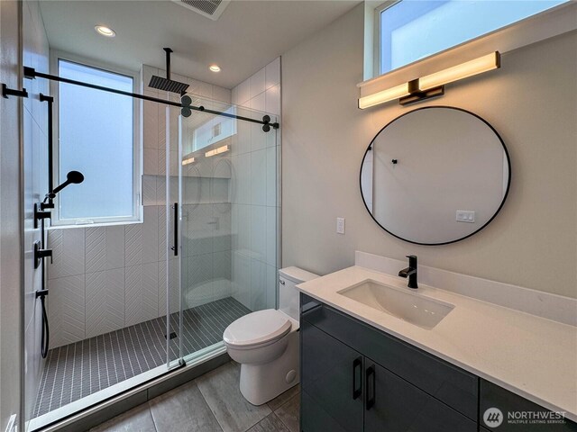 bathroom with toilet, visible vents, a shower stall, and a healthy amount of sunlight