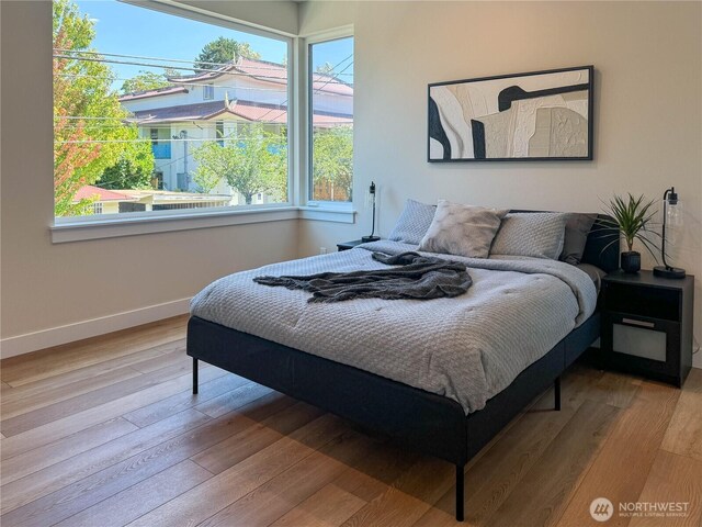 bedroom with baseboards, multiple windows, and wood finished floors