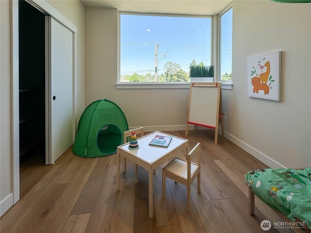 recreation room featuring baseboards and wood finished floors