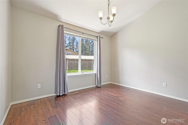 unfurnished room featuring baseboards, a notable chandelier, wood finished floors, and visible vents