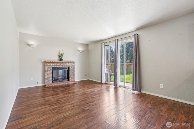 unfurnished living room with baseboards, wood finished floors, and a fireplace