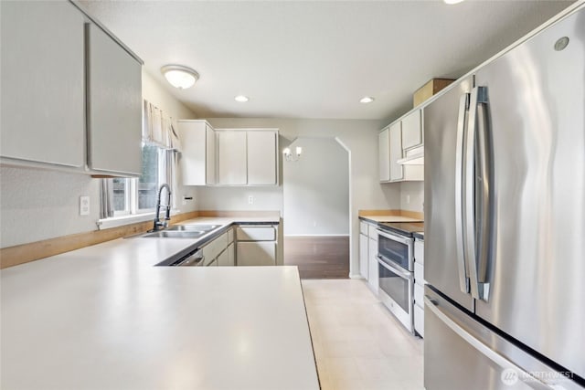 kitchen featuring light floors, recessed lighting, light countertops, a sink, and appliances with stainless steel finishes