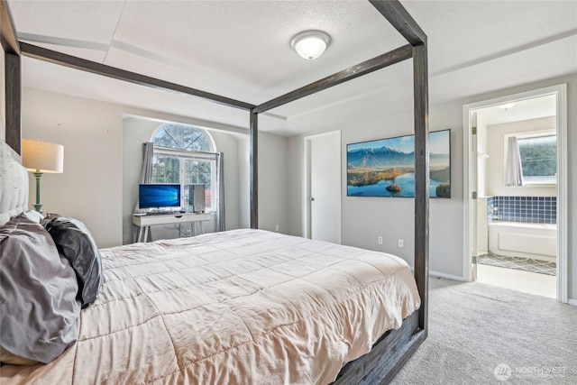 bedroom featuring carpet flooring, ensuite bath, and a textured ceiling