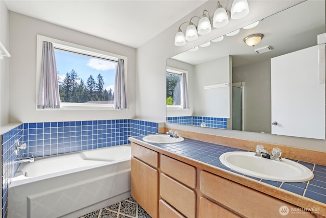 full bath featuring double vanity, visible vents, a sink, and a garden tub