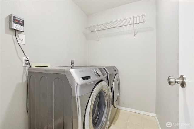 laundry room with laundry area, baseboards, light tile patterned floors, and washing machine and dryer