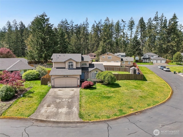 view of front of home with fence, concrete driveway, a garage, and a front yard