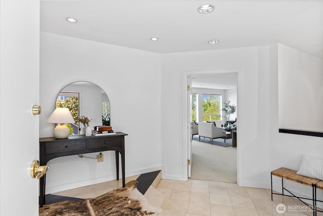 hall featuring recessed lighting, baseboards, light carpet, and light tile patterned floors