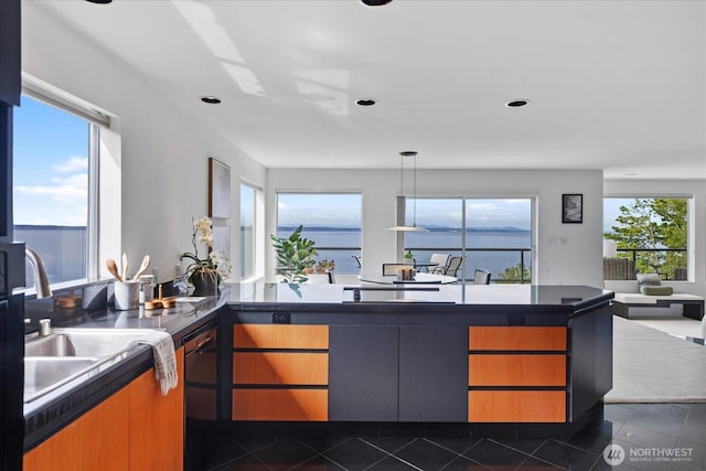 kitchen featuring a peninsula, dark countertops, open floor plan, a sink, and black appliances