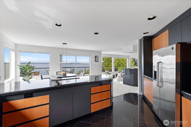 kitchen with stainless steel fridge, granite finish floor, recessed lighting, decorative light fixtures, and open floor plan