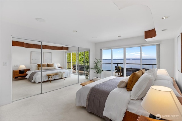 bedroom featuring recessed lighting, carpet flooring, a water view, and access to exterior