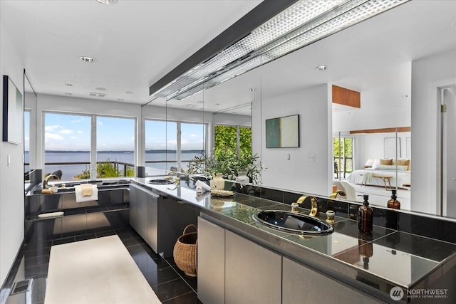 bathroom featuring a water view, tile patterned floors, plenty of natural light, and a sink