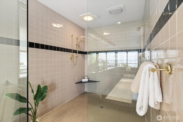 bathroom featuring tile walls and a tile shower