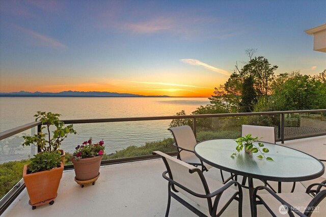 balcony featuring outdoor dining space and a water and mountain view