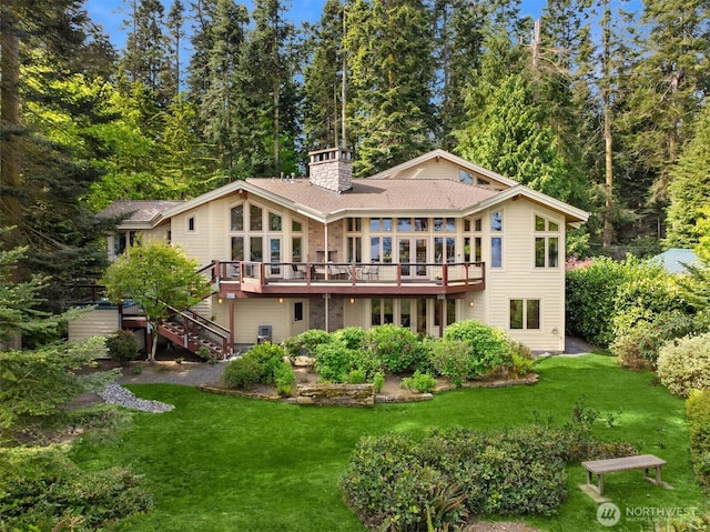 rear view of house featuring a yard, a wooden deck, stairs, and a chimney