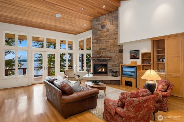 living room featuring wood ceiling, french doors, a stone fireplace, high vaulted ceiling, and light wood-style flooring