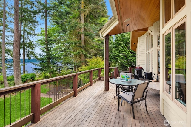 wooden terrace featuring a water view and outdoor dining space