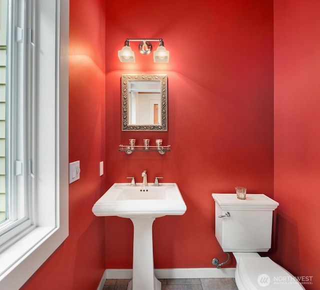 half bath featuring baseboards, tile patterned flooring, and toilet