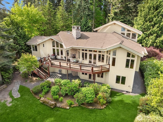 rear view of house featuring a lawn, a chimney, stairs, and a wooden deck