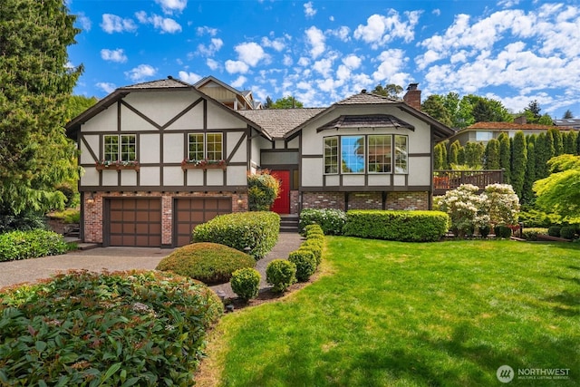 tudor home featuring stucco siding, an attached garage, driveway, and a front yard