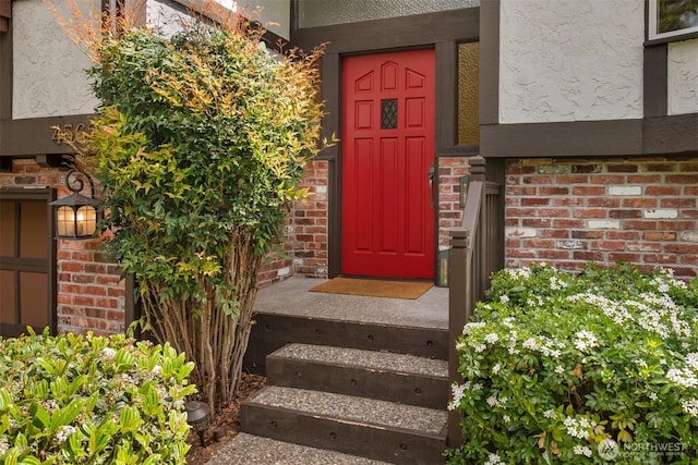 entrance to property featuring brick siding and stucco siding