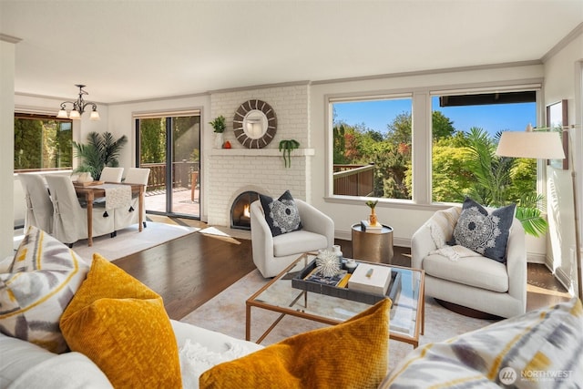 living room with crown molding, a notable chandelier, wood finished floors, and a fireplace