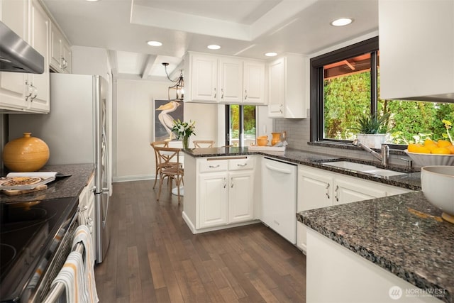kitchen with wall chimney range hood, white dishwasher, plenty of natural light, and a sink