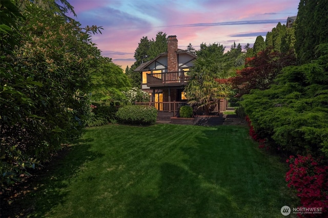 yard at dusk with a wooden deck and a balcony