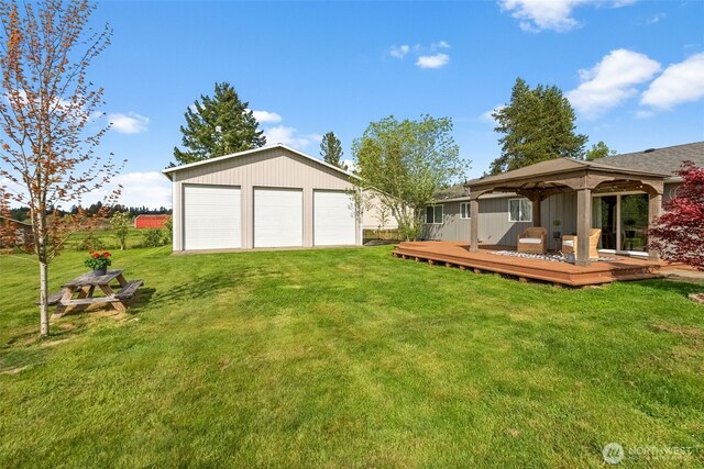 view of yard with a detached garage, a gazebo, an outbuilding, and a wooden deck