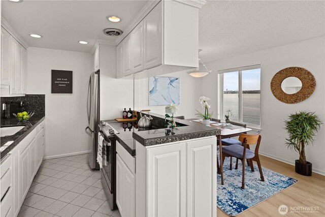 kitchen with electric stove, white cabinets, freestanding refrigerator, tile counters, and recessed lighting