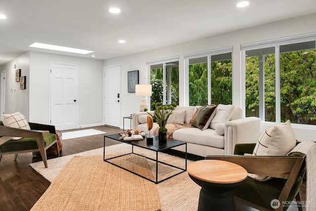 living area with a skylight, recessed lighting, baseboards, and dark wood finished floors