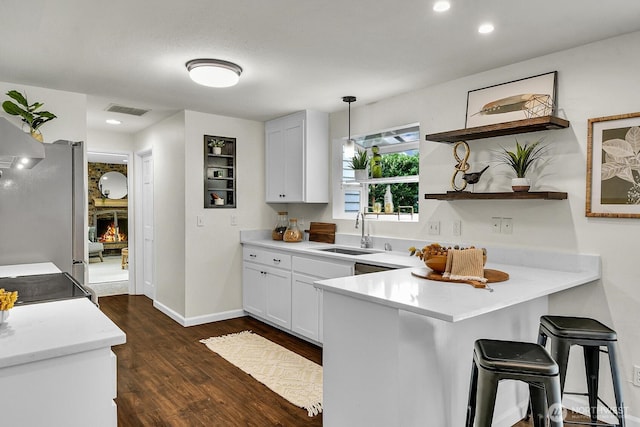 kitchen featuring visible vents, open shelves, freestanding refrigerator, a peninsula, and a sink