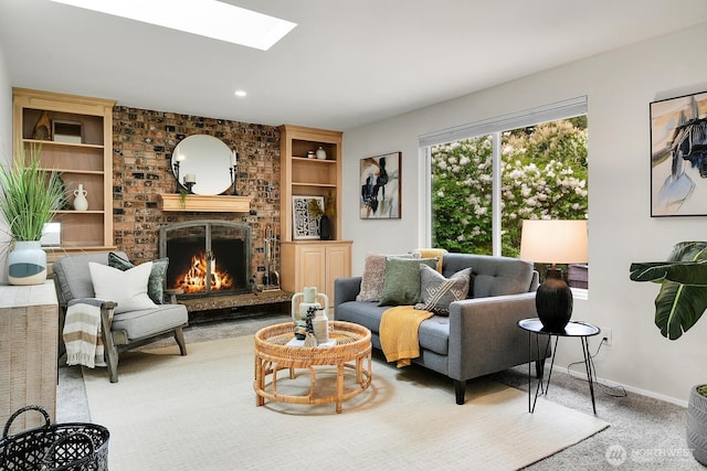 carpeted living room with a skylight, baseboards, a brick fireplace, and built in shelves