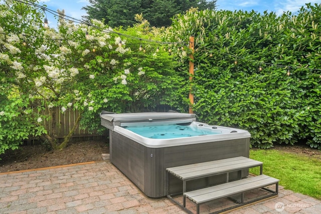 view of patio / terrace featuring a hot tub and fence