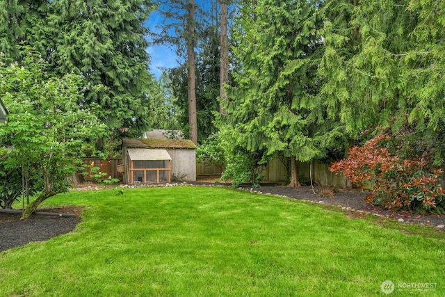 view of yard featuring an outdoor structure, exterior structure, and a fenced backyard