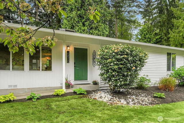 view of exterior entry featuring a lawn