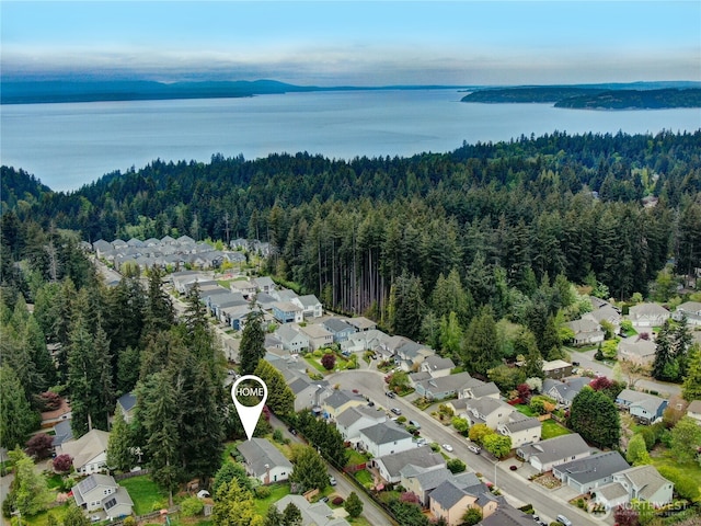drone / aerial view with a water view, a view of trees, and a residential view
