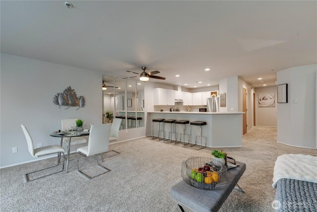 living area with baseboards, ceiling fan, recessed lighting, and light colored carpet