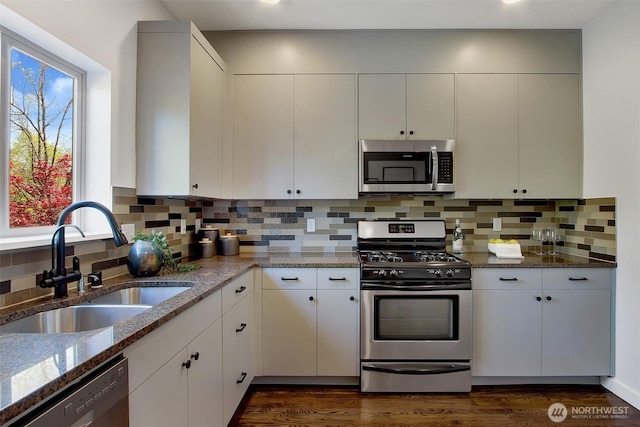 kitchen with stone countertops, appliances with stainless steel finishes, a wealth of natural light, and a sink
