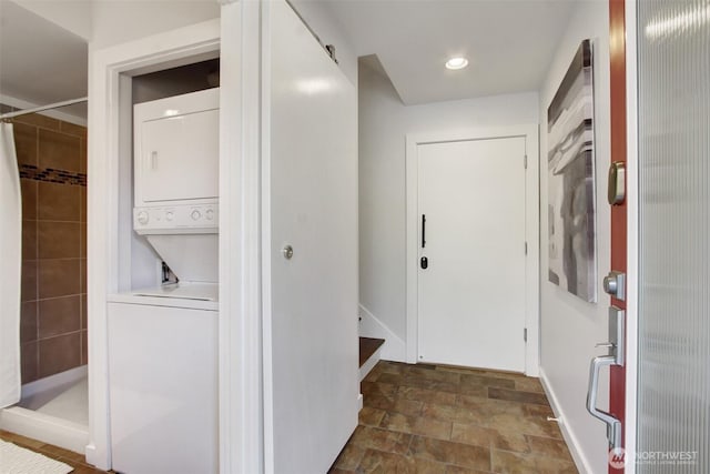 hall featuring stacked washing maching and dryer and stone finish flooring