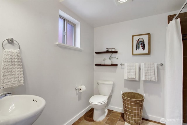 bathroom featuring a sink, baseboards, toilet, and curtained shower