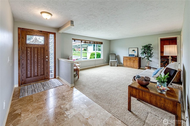 carpeted entrance foyer with baseboards and a textured ceiling
