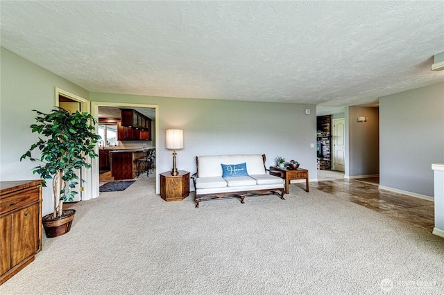 carpeted living room featuring baseboards and a textured ceiling