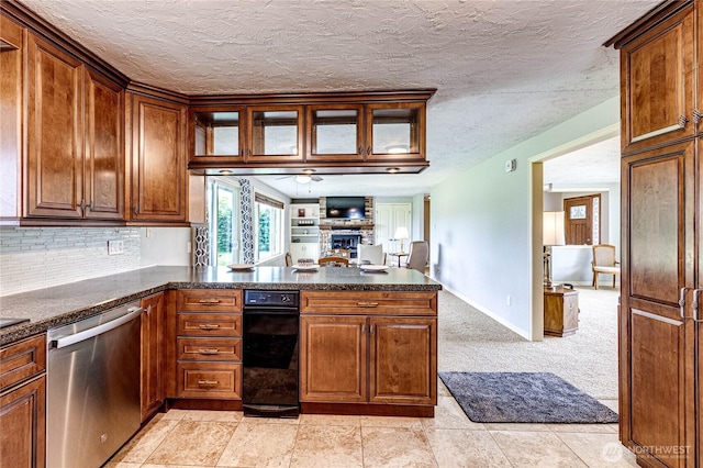 kitchen featuring ceiling fan, dishwasher, a large fireplace, a peninsula, and decorative backsplash